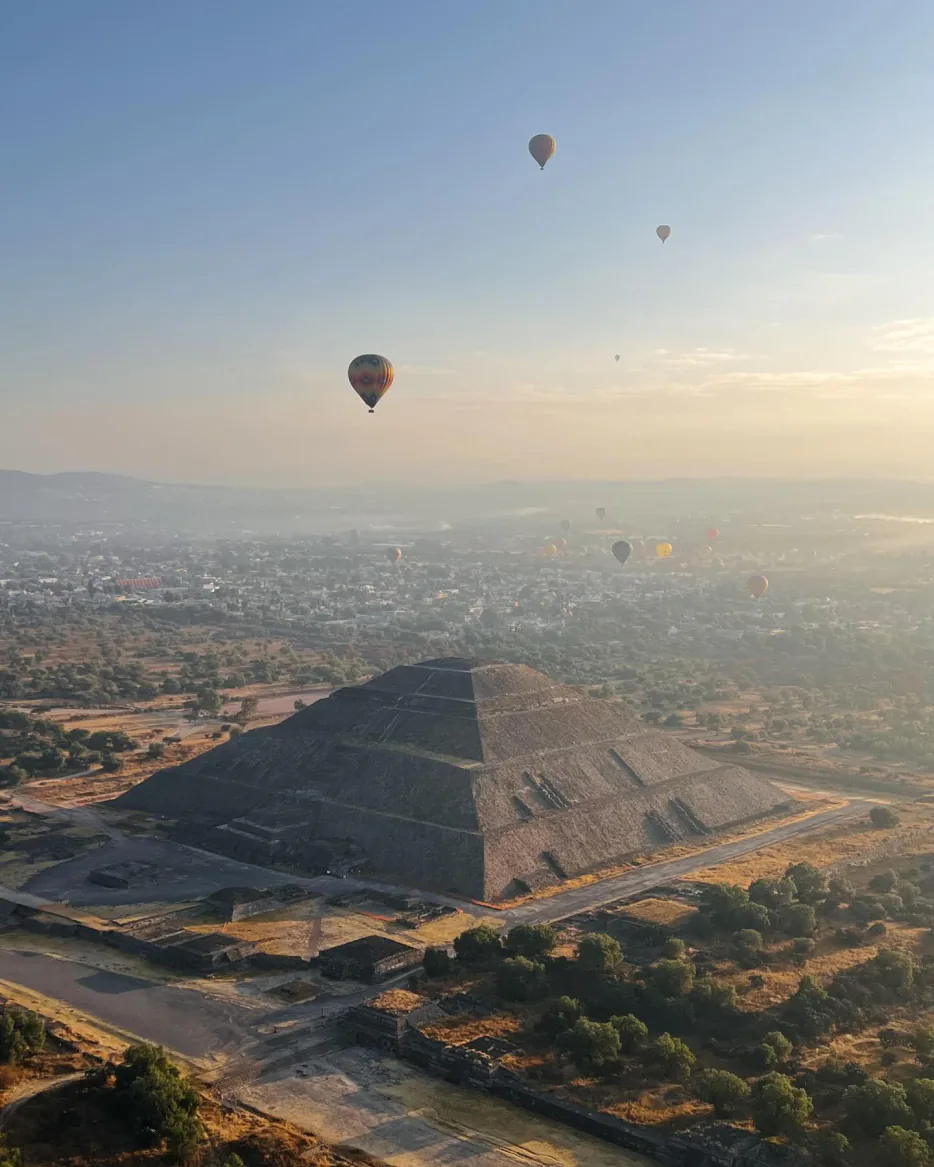 Pirámide del Sol vista desde el aire con decenas de globos aerostáticos sobre el valle brumoso de Teotihuacán